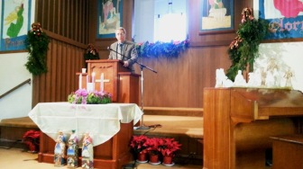 Man preaching surrounded by Christmas decorations